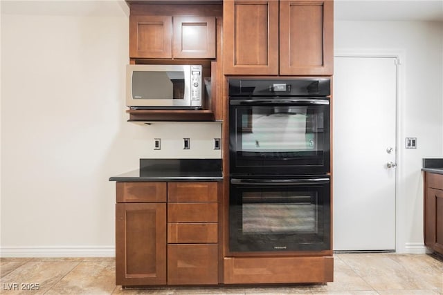 6284 Pinewood Ave, Las Vegas, NV 89103 - kitchen featuring dobule oven black, baseboards, brown cabinetry, stainless steel microwave, and dark countertops
