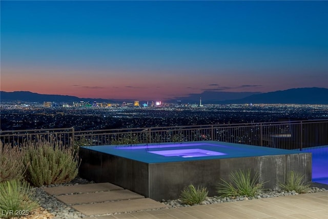 pool at dusk with a jacuzzi and a mountain view