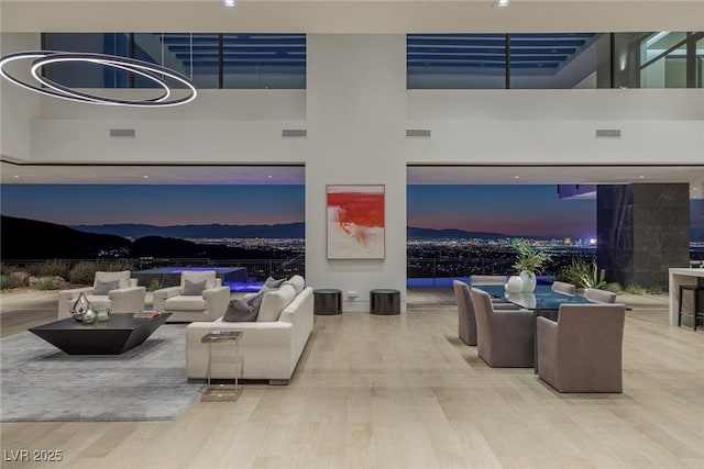 living room featuring visible vents, a towering ceiling, and wood finished floors