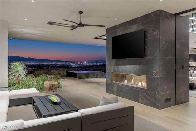 patio terrace at dusk featuring an outdoor living space with a fireplace and ceiling fan