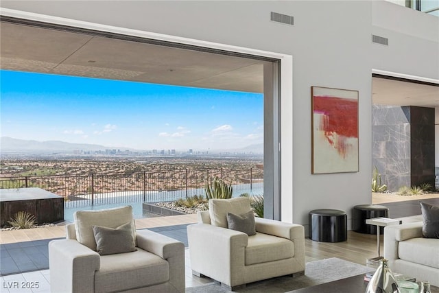 living area featuring a wall of windows, a mountain view, wood finished floors, and visible vents