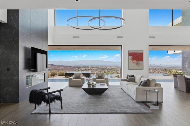 living room featuring visible vents, wood finished floors, and a towering ceiling