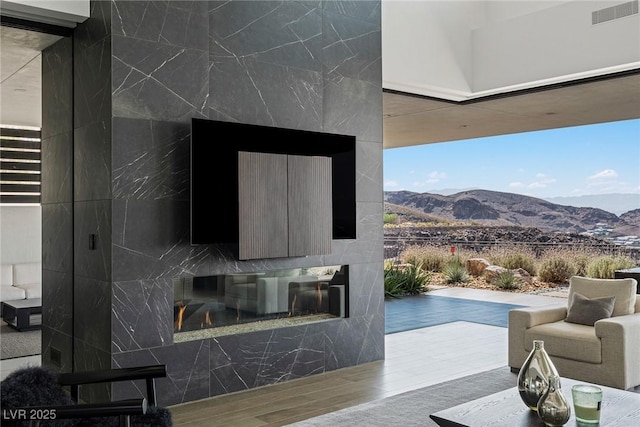 living room with visible vents, a mountain view, a fireplace, and wood finished floors