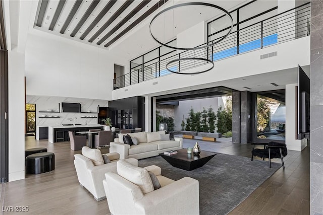 living area with visible vents, a towering ceiling, and wood finished floors