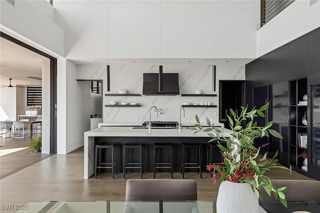 kitchen with light wood finished floors, a breakfast bar, dark cabinetry, modern cabinets, and open shelves