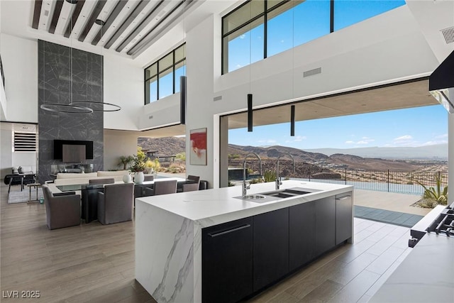 view of patio / terrace with visible vents, an outdoor living space with a fireplace, a sink, a mountain view, and outdoor dining area