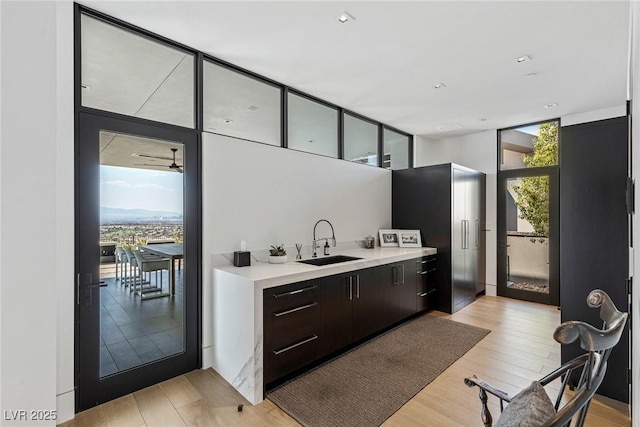 kitchen featuring light wood-type flooring, modern cabinets, a sink, light countertops, and a wall of windows