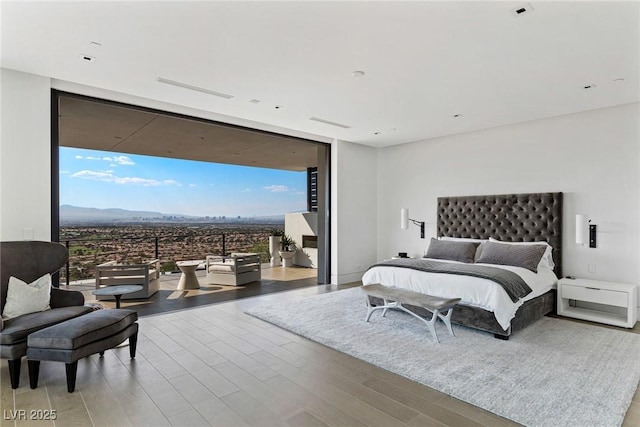 bedroom with access to outside, wood finished floors, a mountain view, and expansive windows