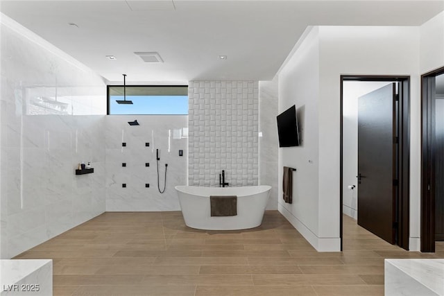 full bath featuring a freestanding tub, wood finished floors, visible vents, and tiled shower