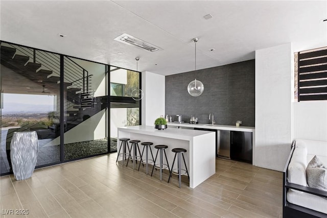 kitchen with modern cabinets, a kitchen breakfast bar, a kitchen island, light countertops, and a wall of windows