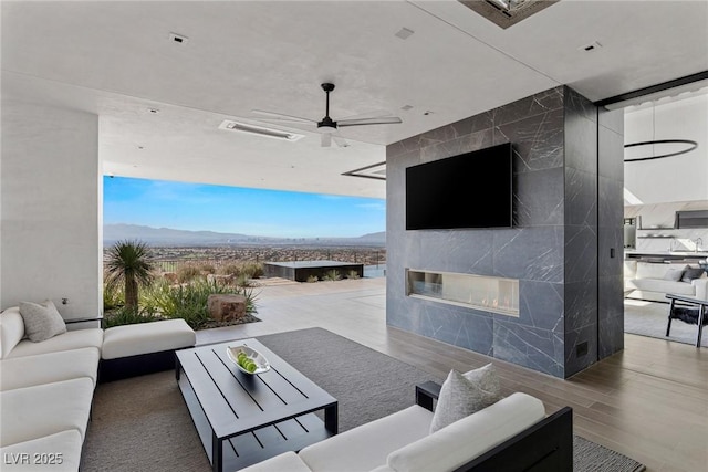 view of patio featuring an outdoor living space with a fireplace, a ceiling fan, and visible vents