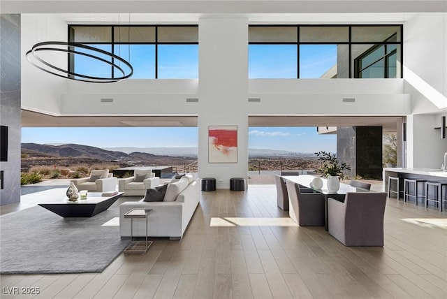 living area featuring visible vents, a mountain view, a high ceiling, and wood finished floors