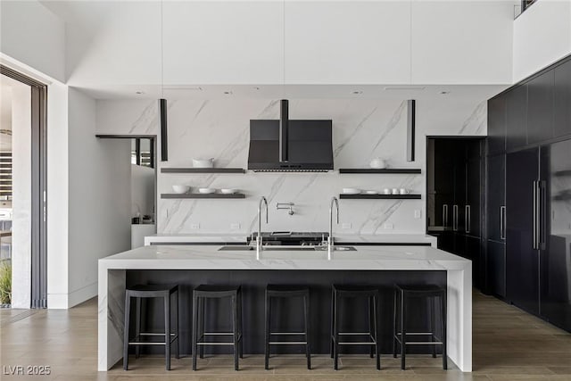 kitchen with modern cabinets, light wood-style flooring, open shelves, dark cabinetry, and decorative backsplash