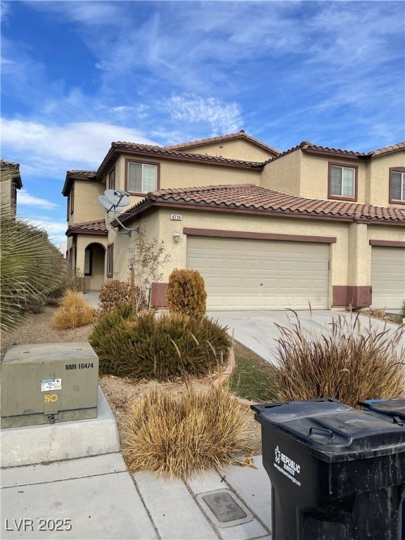 view of front facade featuring a garage, concrete driveway, a tiled roof, and stucco siding