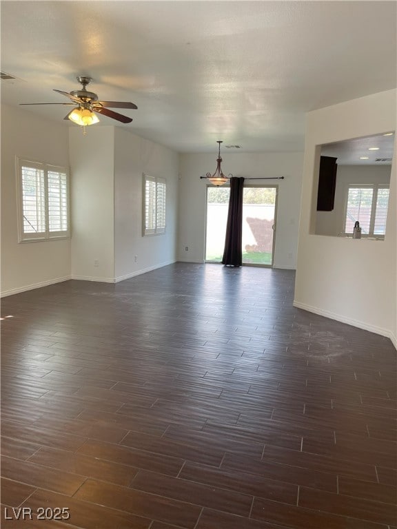 unfurnished room featuring a ceiling fan, visible vents, dark wood finished floors, and baseboards