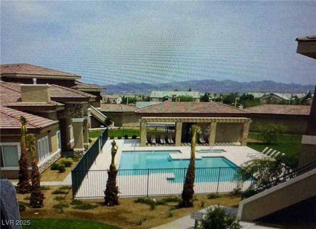 pool with a patio area, fence, and a mountain view