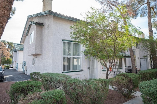 view of property exterior with a chimney and stucco siding