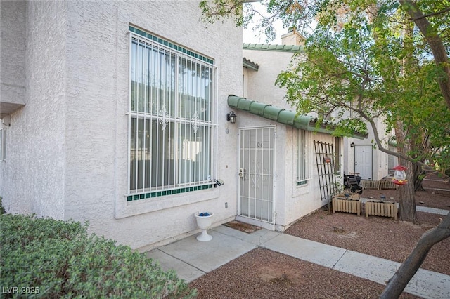 entrance to property with a tiled roof, a chimney, and stucco siding