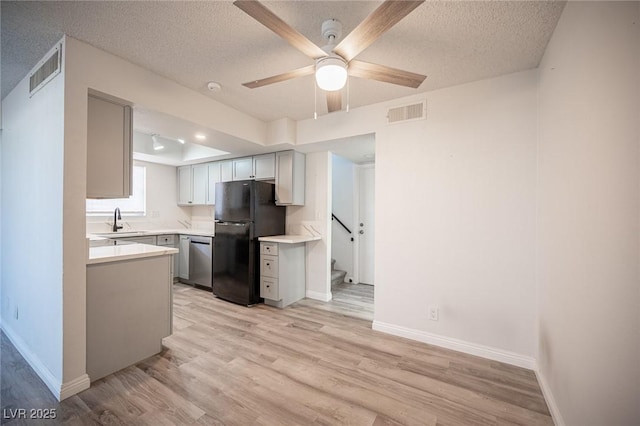 kitchen featuring a sink, visible vents, light wood-type flooring, freestanding refrigerator, and dishwasher