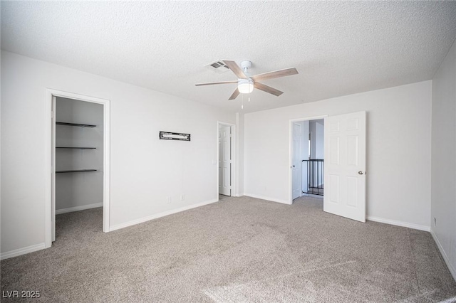 unfurnished bedroom featuring carpet, visible vents, a spacious closet, and a textured ceiling