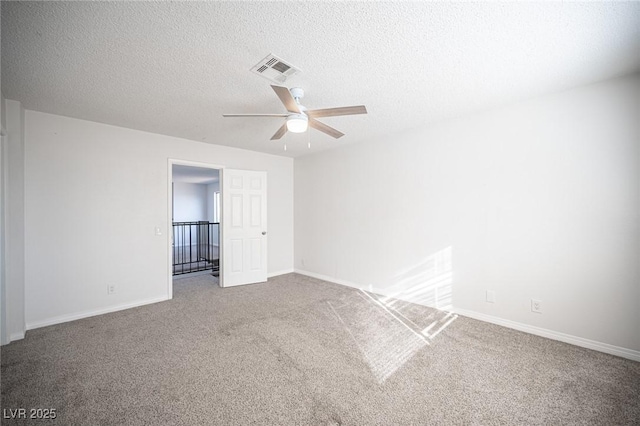 carpeted spare room featuring a ceiling fan, baseboards, visible vents, and a textured ceiling