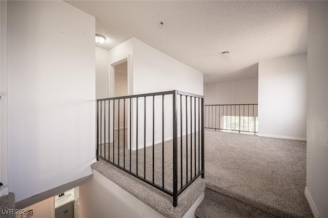 hall featuring carpet, a textured ceiling, and baseboards