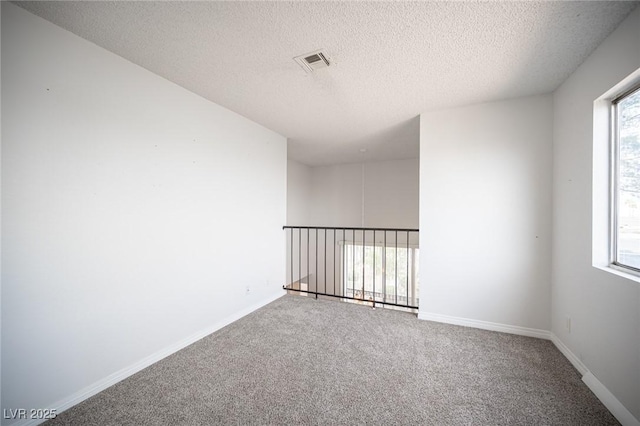 unfurnished room featuring carpet floors, baseboards, visible vents, and a wealth of natural light