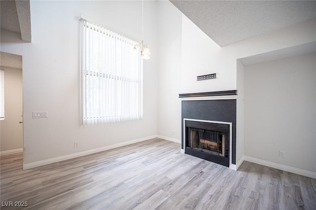 unfurnished living room with baseboards, lofted ceiling, wood finished floors, a textured ceiling, and a fireplace