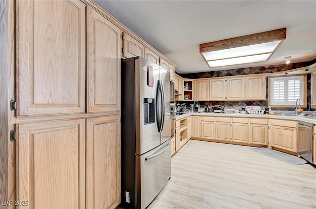 kitchen featuring light brown cabinets, stainless steel appliances, a sink, light countertops, and light wood-type flooring