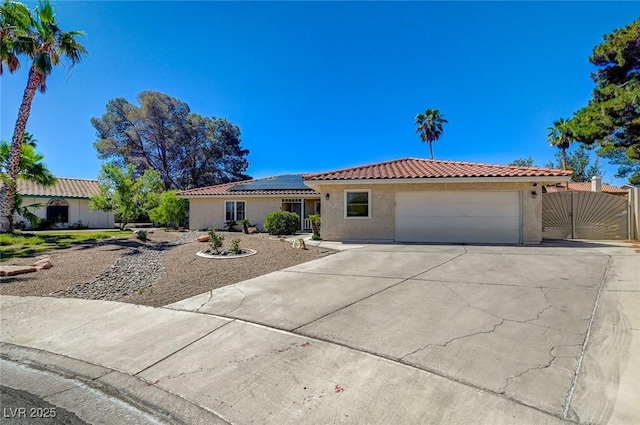 view of front facade with concrete driveway, a gate, a tiled roof, and stucco siding