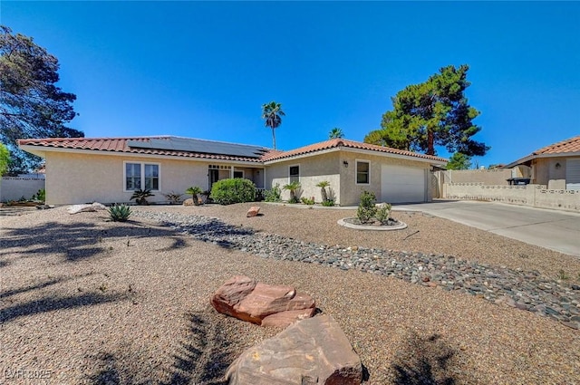 view of front of house featuring an attached garage, concrete driveway, a tiled roof, roof mounted solar panels, and stucco siding