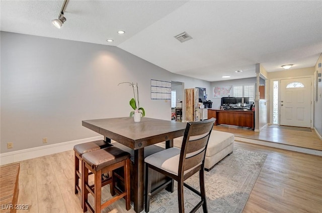 dining room with vaulted ceiling, light wood finished floors, visible vents, and baseboards