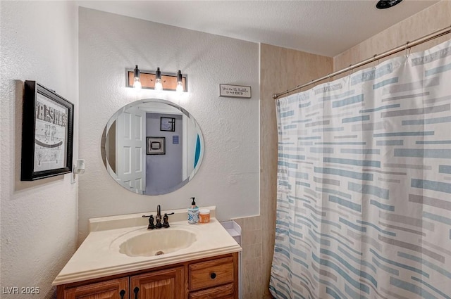 bathroom with a shower with shower curtain, a textured wall, a textured ceiling, and vanity