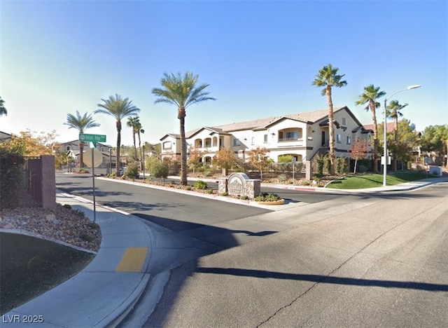 view of road featuring street lighting, traffic signs, sidewalks, a residential view, and curbs