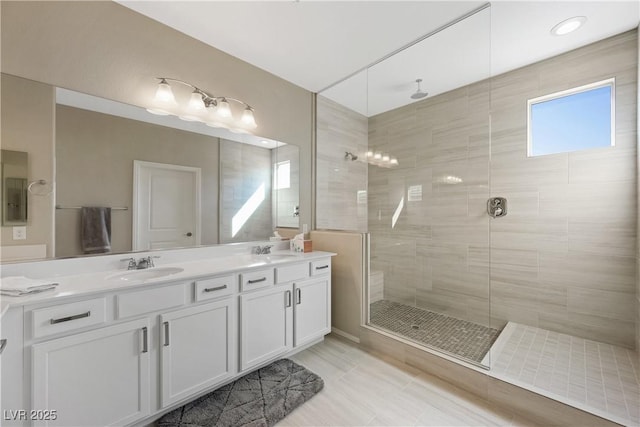 bathroom with double vanity, a tile shower, and a sink