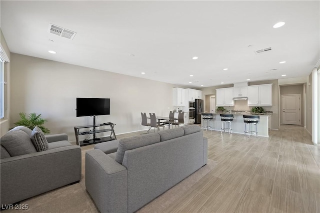 living room featuring baseboards, visible vents, and recessed lighting