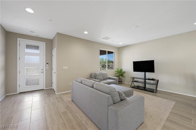 living area featuring baseboards, visible vents, light wood-style flooring, and recessed lighting