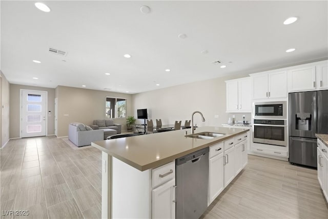 kitchen featuring stainless steel appliances, recessed lighting, visible vents, a sink, and an island with sink