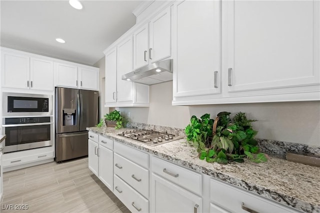 kitchen featuring stainless steel appliances, white cabinetry, under cabinet range hood, and light stone counters