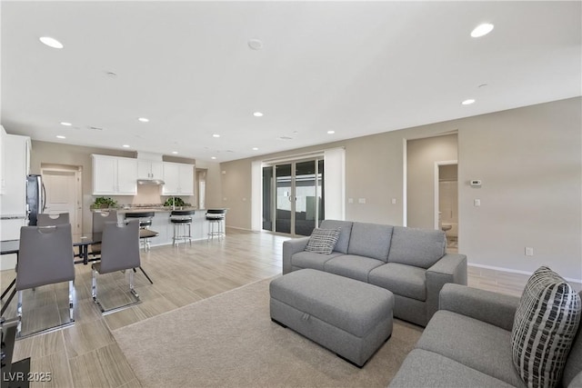 living room with light wood-type flooring, recessed lighting, and baseboards