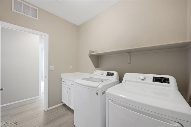 clothes washing area featuring cabinet space, baseboards, visible vents, washing machine and clothes dryer, and wood tiled floor