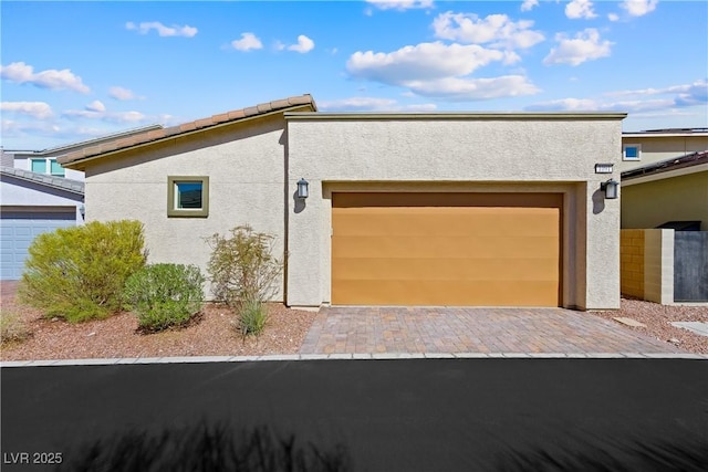 exterior space with decorative driveway, an attached garage, and stucco siding