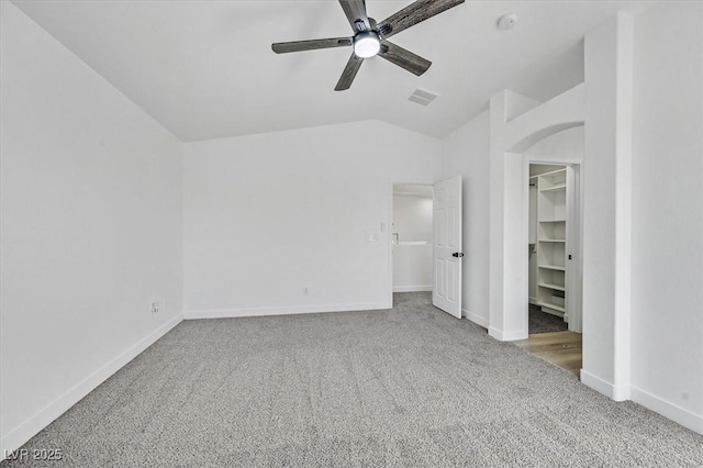 unfurnished bedroom with carpet, lofted ceiling, visible vents, a spacious closet, and baseboards