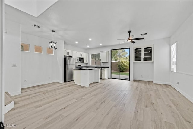 kitchen featuring dark countertops, visible vents, appliances with stainless steel finishes, open floor plan, and white cabinets