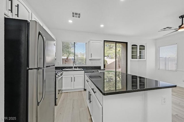 kitchen with visible vents, light wood-style flooring, a kitchen island, stainless steel appliances, and a sink