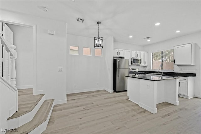 kitchen featuring stainless steel appliances, dark countertops, visible vents, and white cabinetry