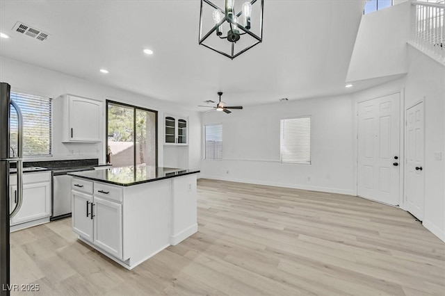 kitchen with light wood-style floors, dark countertops, visible vents, and white cabinetry