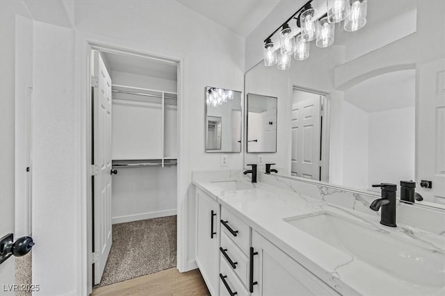 full bath featuring double vanity, wood finished floors, a sink, and a walk in closet