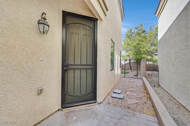 entrance to property with fence and stucco siding