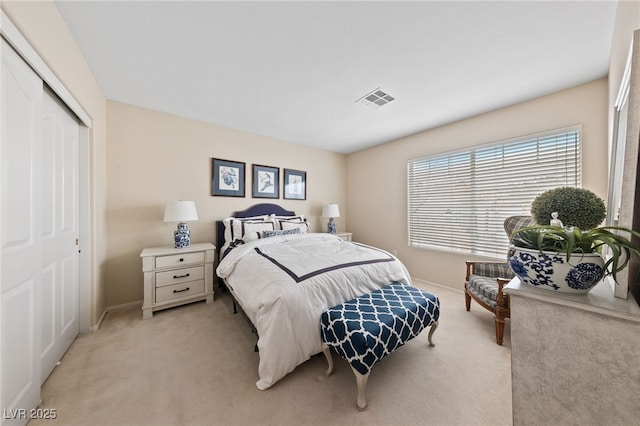 bedroom featuring a closet, visible vents, light carpet, and baseboards